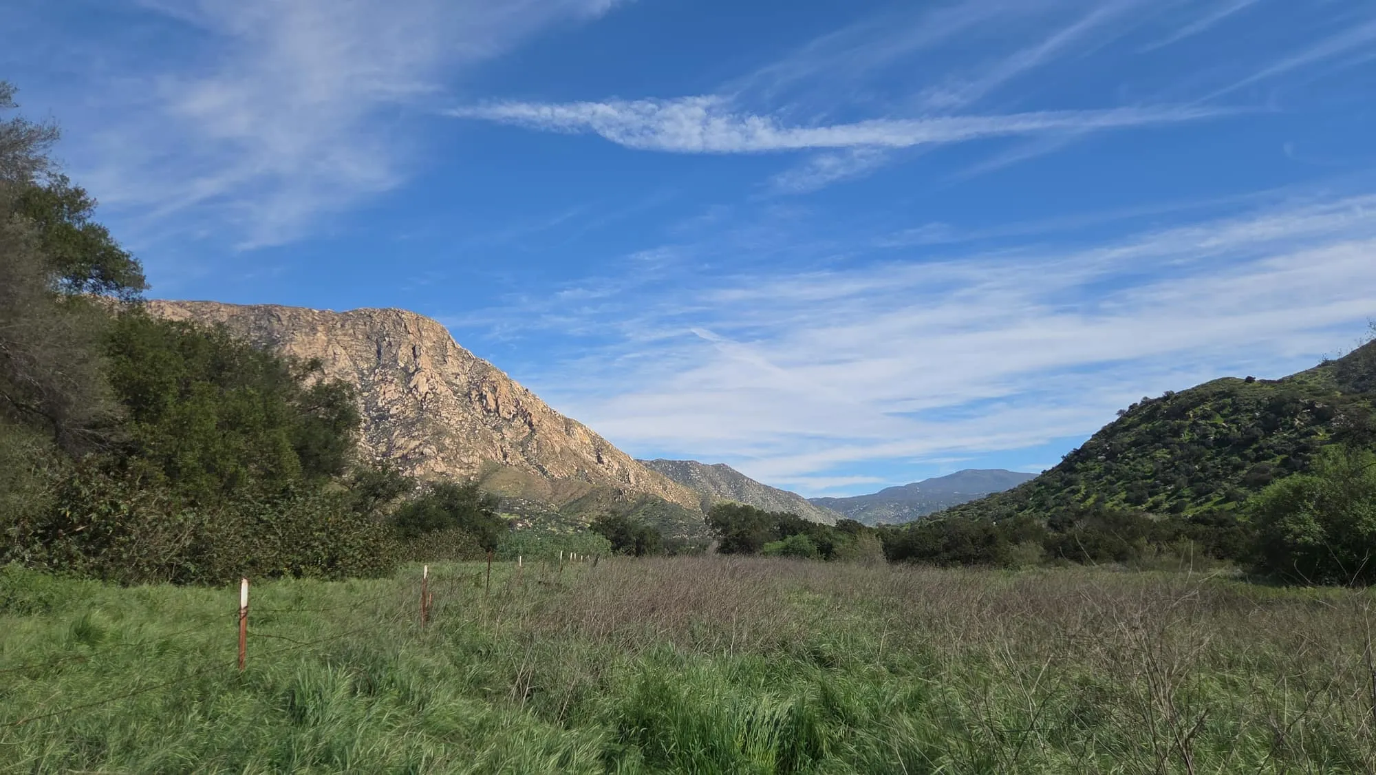 A green valley below a rocky peak at a GSLC-protected preserve